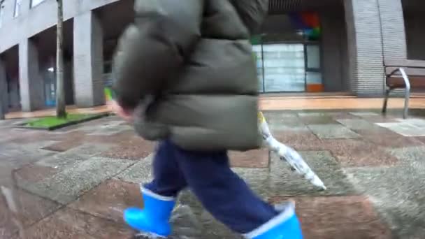 Mavi Lastik Çizmeli Bir Çocuğun Ayakları Yağmurda Birikintisinin Üzerinden Atlıyor — Stok video