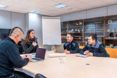 Bir grup mühendis toplantı sırasında toplantı odasında birlikte oturuyorlar.