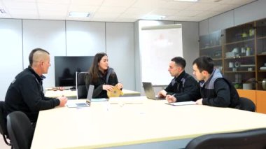Bir grup mühendis toplantı sırasında toplantı odasında birlikte oturuyorlar.