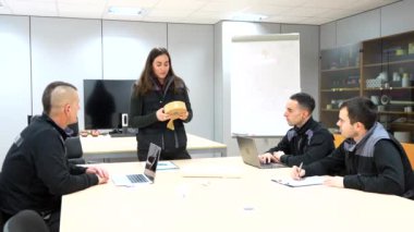 Mühendislerle masa ve yemek olan bir fabrika odasında toplantı düzenleyen müdür.