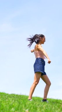 Kafkasyalı esmer kadın, parkın tepesinde dans ediyor, gülümsüyor, amuda kalkıyor.