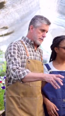 Çiçek bakıcıları seradaki bitkileri kontrol ediyor.