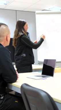 Bir fabrikanın toplantı odasında mühendislerle beyin fırtınası yaparken tahtayı kullanan bir kadın.
