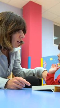 Masada oturan bir çocuğun portresi masal kitabı okuyor, bir anaokulunun içinde.