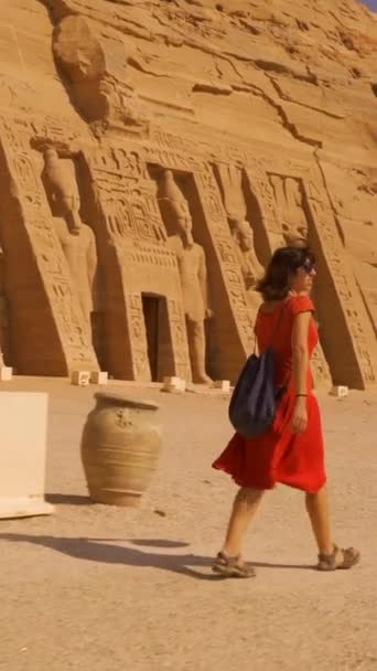 在埃及南部努比亚靠近纳赛尔湖的阿布辛贝尔神庙旁边 一名身穿红色衣服的年轻女子走向尼夫塔里神庙 Pharaoh Ramses Ii圣殿 4K视频 — 图库视频影像