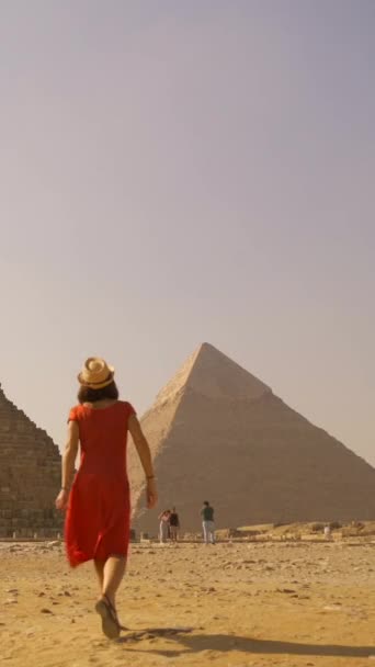 Kırmızı Elbiseli Hasır Şapkalı Genç Bir Turistin Giza Piramitlerinde Yürürken — Stok video