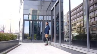 Ampüte edilmiş bacağı olan bir iş adamı, finans caddesi boyunca gidip gelirken cep telefonuyla konuşuyor.