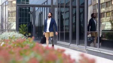 Protez bacaklı bir işadamı, bir finans bölgesinde gidip gelirken cep telefonuyla konuşuyor.