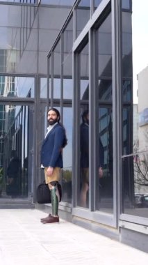 Ampüte edilmiş bacağı olan bir iş adamı, finans caddesi boyunca gidip gelirken cep telefonuyla konuşuyor.