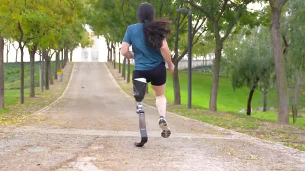 Rückansicht Eines Sportlers Mit Beinprothese Der Durch Einen Park Läuft — Stockvideo