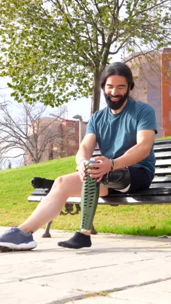 都市公園のベンチに座る前に義足を調節する身体的に障害のある男性 — ストック動画