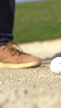 Sığınakta golf oynayan bir adamın ayakları topa sopayla vuruyor.