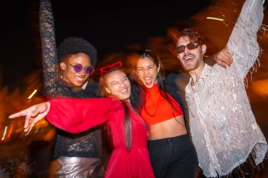 Gece flaşlı ve çok ırklı arkadaşların şehir gecesinde eğlendiği bir fotoğraf.