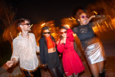 Gece fotoğrafı ve dört şık arkadaşın sokakta dans edişleri.