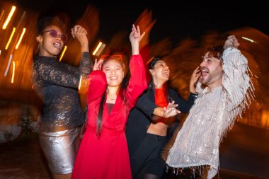 Gece flaşlı ve hareketli mutlu arkadaşlar şehirde eğleniyor ve dans ediyor.