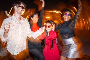 Gece fotoğrafı ve dört farklı etnik gruptan arkadaşın sokakta parti yapmaları.