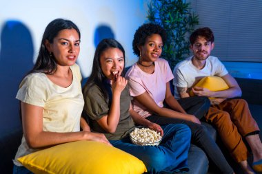 Mutlu arkadaşlar evde film gecesi patlamış mısır yiyorlar.