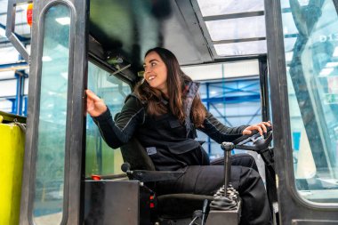 Fabrikada forklift kullanan bir kadının penceresinden bakıyor.