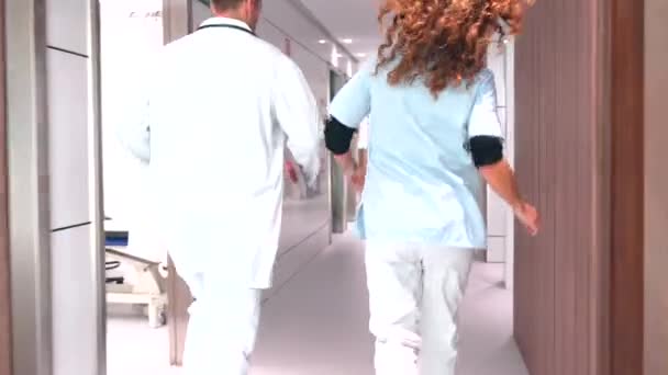 病院の廊下で話している女性看護師と医師のチームワーク — ストック動画