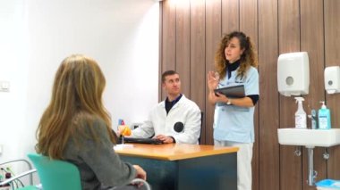 Erkek yakışıklı doktor, tıbbi konsültasyonda yetişkin bir kadın hastaya bakıyor.