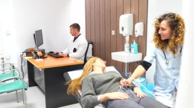 Hemşire, hastanede sedyede yatan bir kadının karnına ultrason yapıyor.