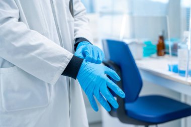 Hastanenin laboratuarında koruyucu lateks küreler giyen bir doktor.