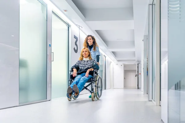 Healthcare worker pushing a wheelchair with injured woman in the hospital corridor