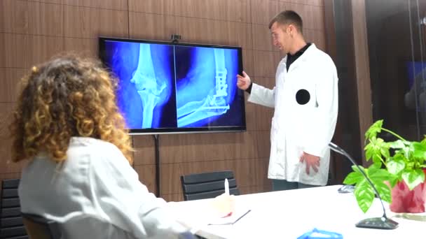 外傷学の会議室でヒップのX線スキャンを見ている医師 — ストック動画