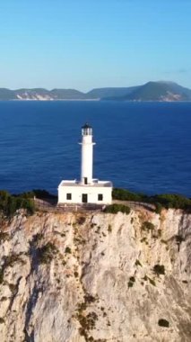 Lefkada adasının güney bölgesinde gün batımında beyaz deniz feneri veya Cape Ducato Lefkas 'ın insansız hava aracı görüntüsü. Yunanistan. Dönen pan düzlemi