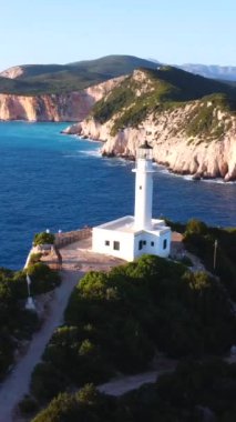 Uçurumların ve beyaz deniz fenerinin hava aracı görüntüsü ya da Lefkada adasının güney bölgesinde gün batımında Ducato Lefkas Burnu. Yunanistan. Dönen pan düzlemi