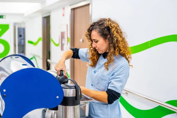 Nurse pouring coffee into cup in the corridor of an hospital using a trolley to carry it