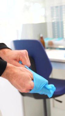 Hastanenin laboratuarında mavi lateks eldiven kullanan bir doktorun yakın çekimi.