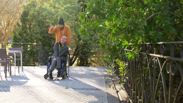 Hombre Discapacitado Relajado Con Silla Ruedas Amigos Paseando Parque Urbano — Vídeos de Stock