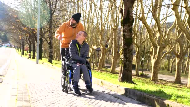 Vårdgivare Som Pekar Framåt Och Pratar Med Handikappad Man Stadspark — Stockvideo