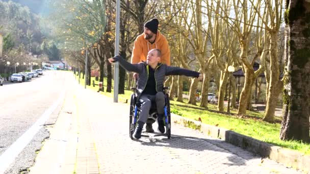 Hombre Discapacitado Sentado Silla Ruedas Amigo Disfrutando Naturaleza Apuntando Mirando — Vídeo de stock