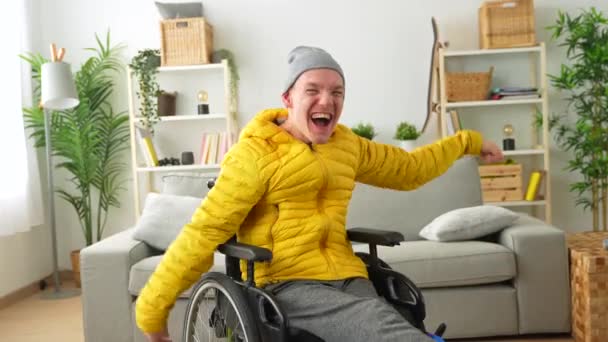 自宅のリビングルームで祝う喜びで手を挙げている車椅子の幸せな障害者の肖像 — ストック動画