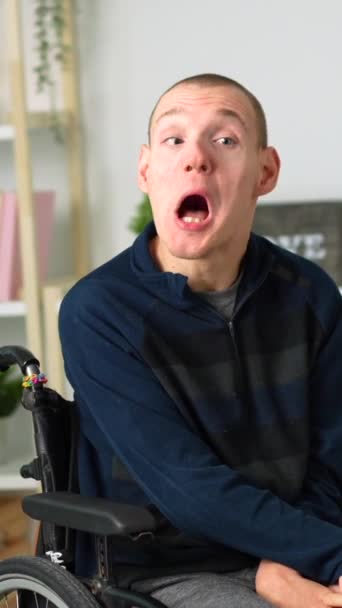 一个坐在轮椅上的快乐的残疾人在家里冷冰冰地对着相机笑的画像 — 图库视频影像