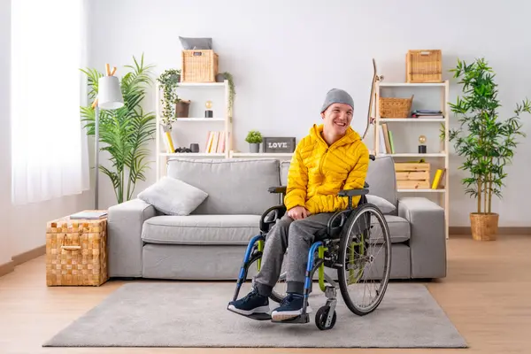 Portrait with copy space of a happy disabled man in warm clothes using wheelchair in the living room