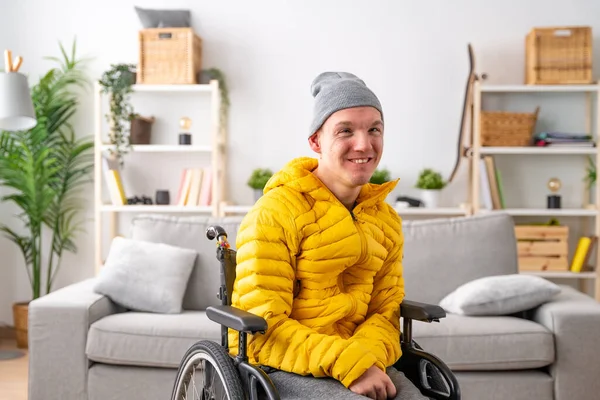Portrait of a smiling man with special needs in wheelchair in the living room at home