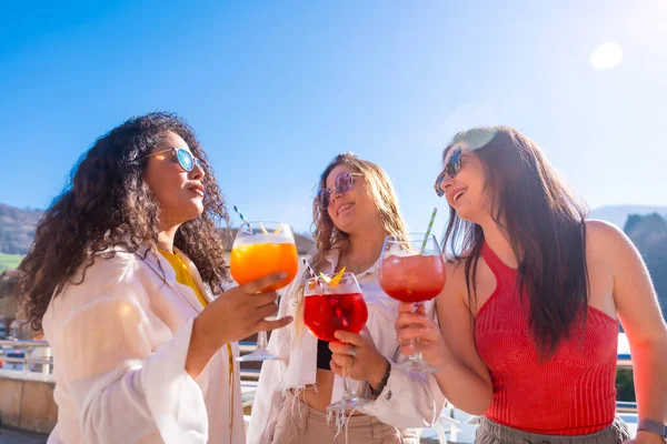 Women enjoying a sunny day drinking cocktails and partying in a roof top
