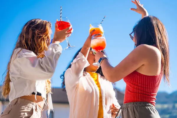 Women celebrating life and summer in a rooftop dancing and drinking alcohol