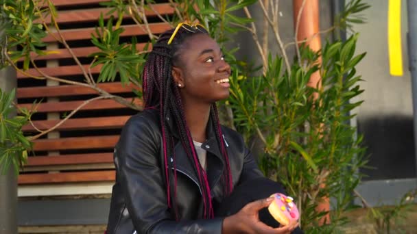 Cool Afrikaanse Vrouw Met Een Veelkleurige Zoete Donut Glimlachen Camera — Stockvideo