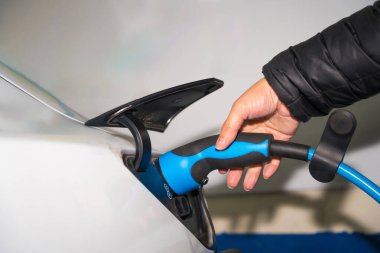 Garajında elektrikli araba şarjı olan bir adamın eli.