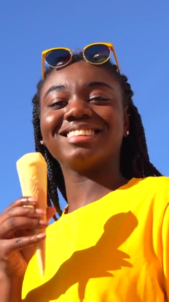 有辫子的非洲女人在阳光下吃着冰激凌 背景是蓝天 — 图库视频影像