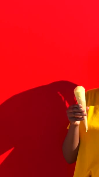 Ευτυχισμένη Νεαρή Αφρικανή Που Τρώει Παγωτό Ακουμπισμένη Στον Κόκκινο Τοίχο — Αρχείο Βίντεο