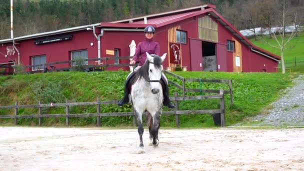 穏やかな馬場で白馬に乗っている若い女性の正面の景色 — ストック動画