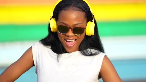非洲妇女在五彩缤纷的城市公园里用耳机听音乐 — 图库视频影像