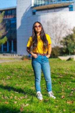 Üniversite binasının yanındaki kampüste güneş gözlüklü güzel Asyalı öğrenci.