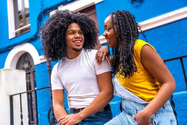 stock image Cool african couple looking at each other sitting in the street with colorful houses