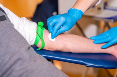 Bölgeyi temizleyen hemşire pamuklu bez kullanarak kan donörünün koluna iğne batıracak.